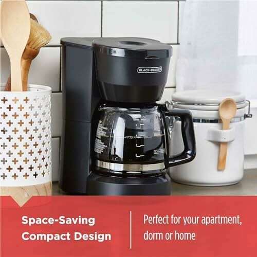 Compact coffee maker on a kitchen counter with utensils and containers.